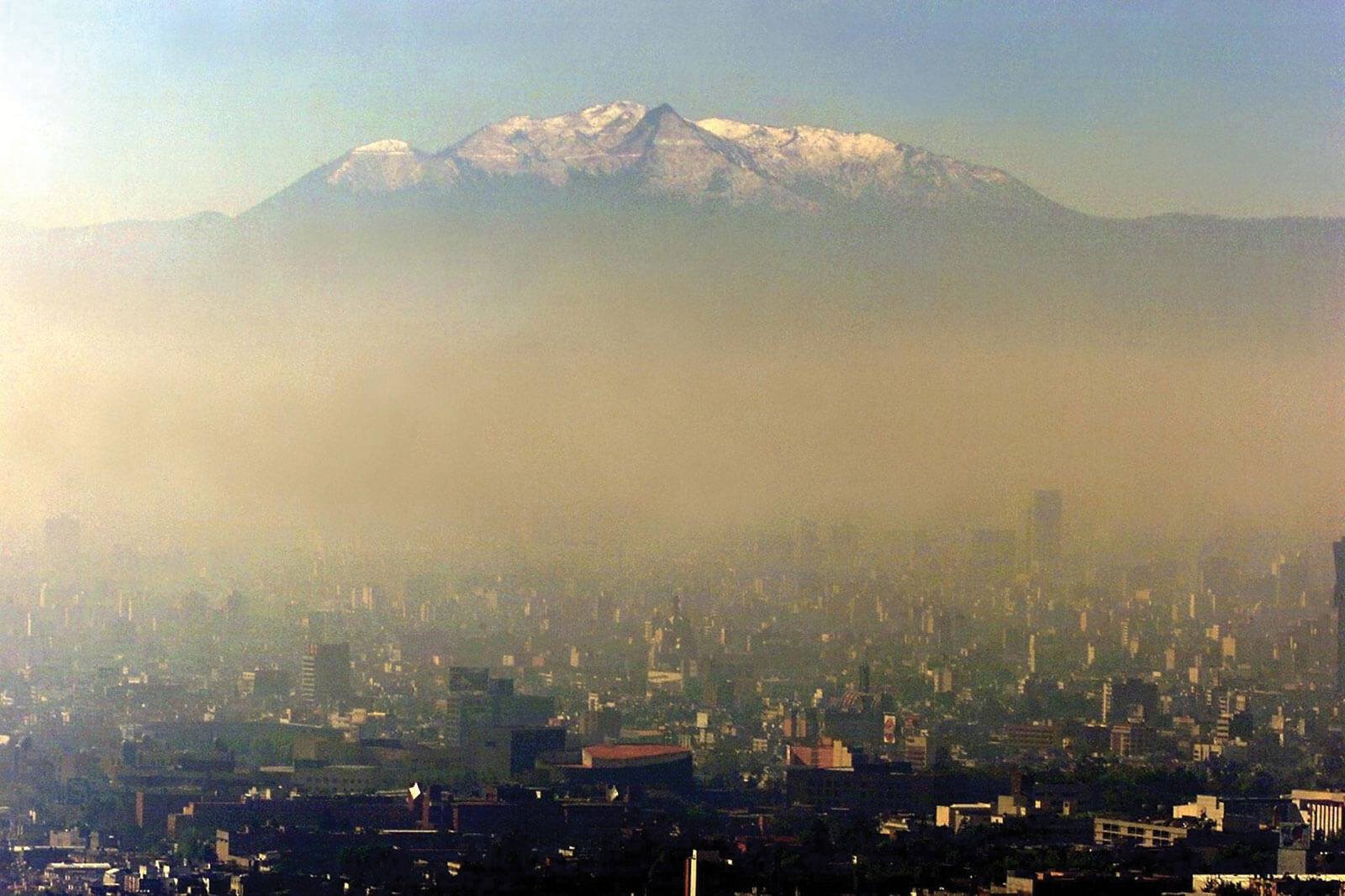 PanorÃ¡mica de Ciudad de MÃ©xico. De fondo se ve el volcÃ¡n  IztaccÃ­huat y en primer plano las edificaciones de la ciudad. Cabe destacar la presencia de un gruesa capa de nubosidad contaminante entre el volcÃ¡n y las edificaciones.